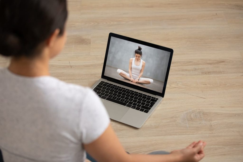 Girl-sitting-infront-pf-laptop-doing-yoga