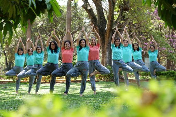 Group of people doing Vrikshasana- treepose in a garden with blurred bg